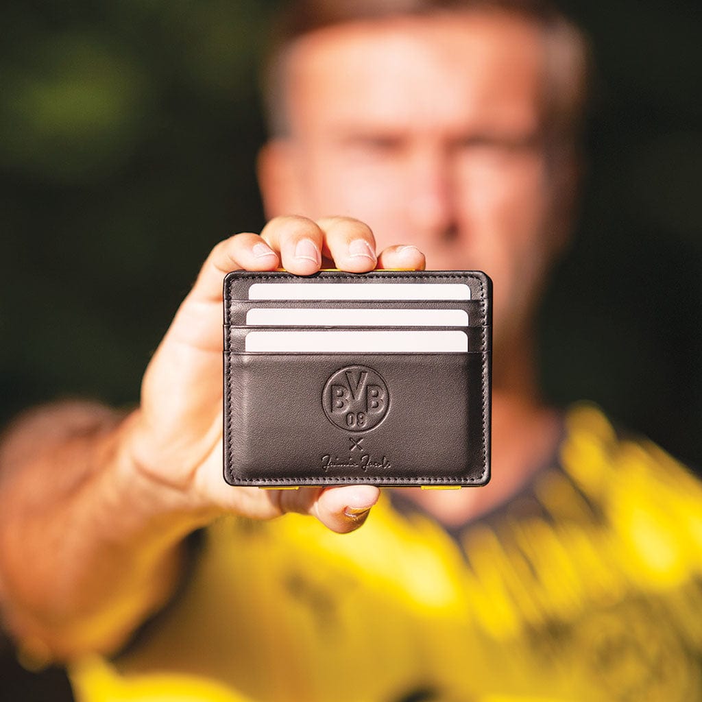 fan hält den flap boy slim geldbeutel der borussia dortmund edition in die kamera 